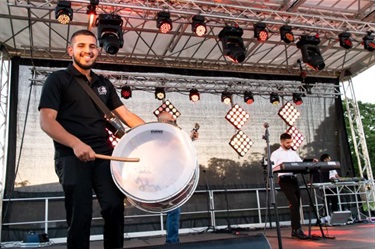 Assyrian drummer performing on stage with band members