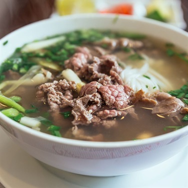 Bowl of beef Pho, beef broth over rice noodles, thinly sliced beef and green onion