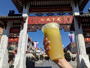 Person holding a sugar cane drink in front of Pai Lau Gate