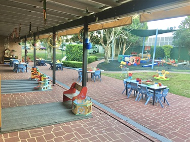 Tables with different toys and activities located near the playground equipment in the children's outdoor area