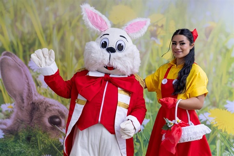 Easter Bunny waving to the camera accompanied by chaperone.