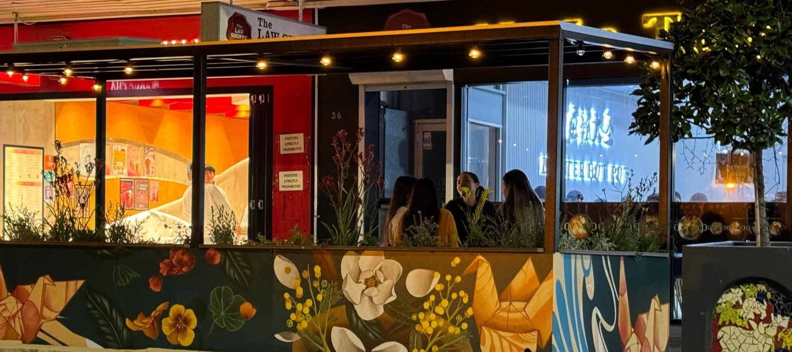 3 ladies siting at a parklet and talking at night.