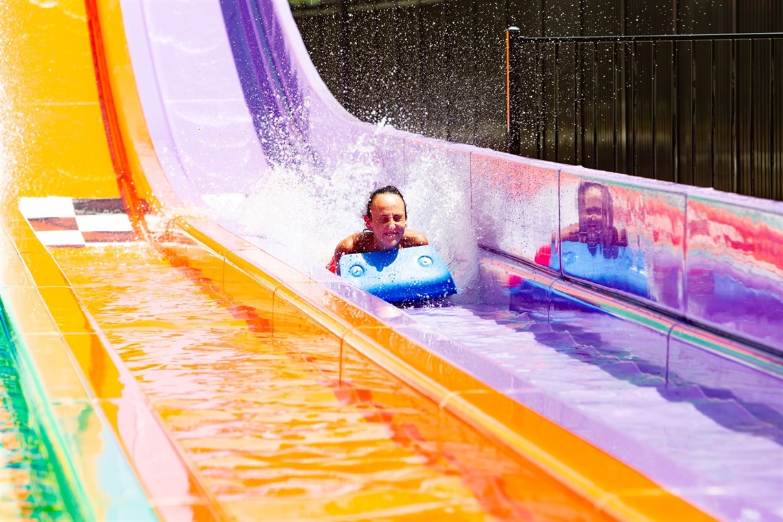 Young woman sliding down one of the three lane racing ride slides