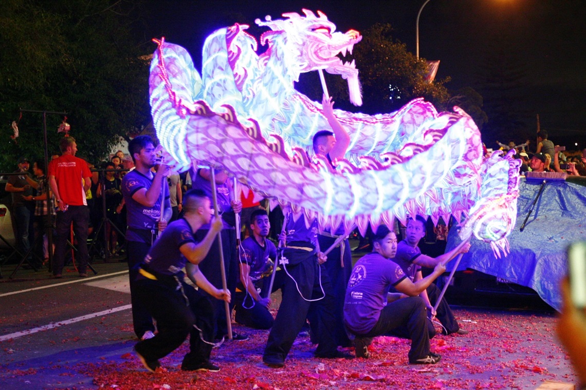 Group of young men performing with light up dragon dancing puppet