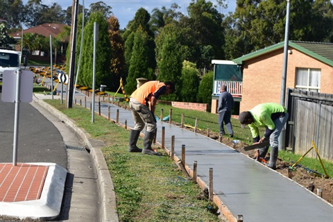 Men wearing high visibility vests completing the construction of new footpaths 