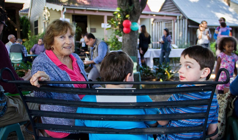 Elderly woman sitting on a bench and smiling with two young boys